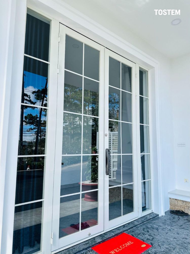 Cửa nhôm kính chia ô màu trắng tinh tế, tạo điểm nhấn ấn tượng cho mặt tiền nhà phố
